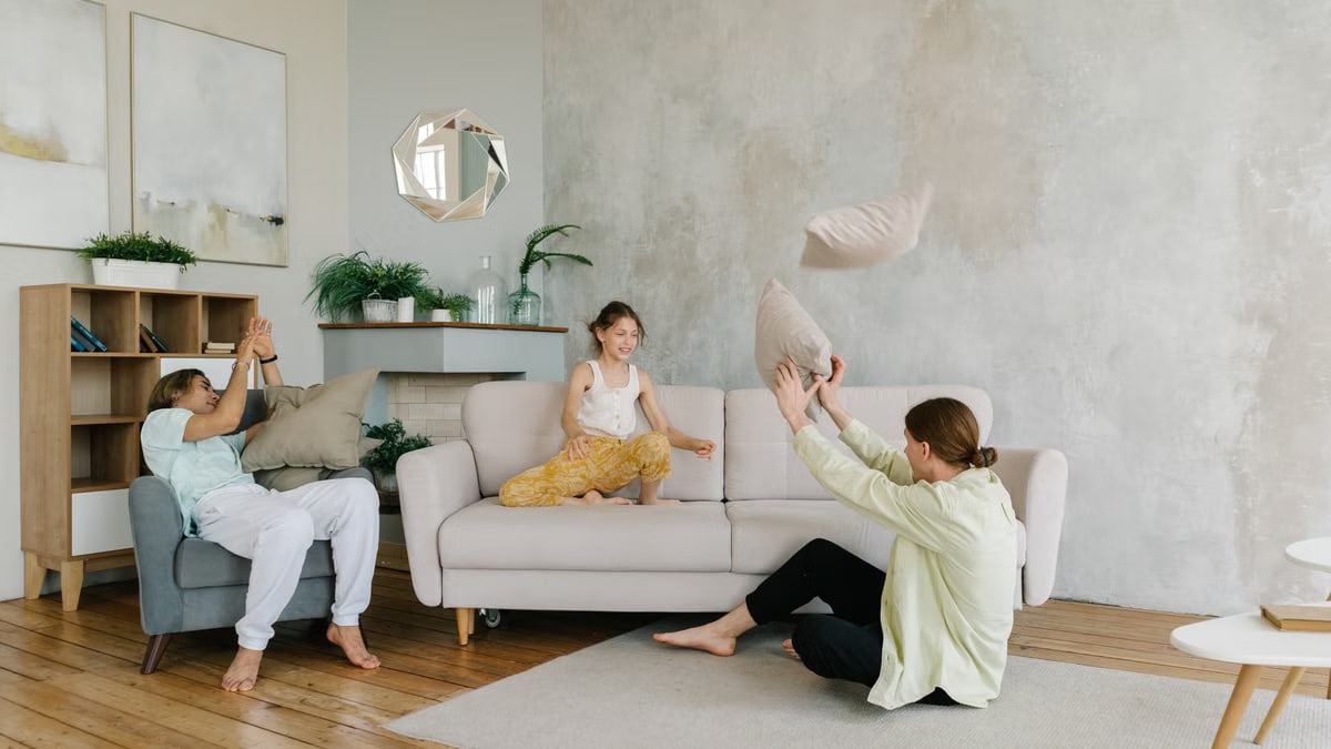 A happy family enjoying playful bonding time at home by tossing pillows in a cozy living room.